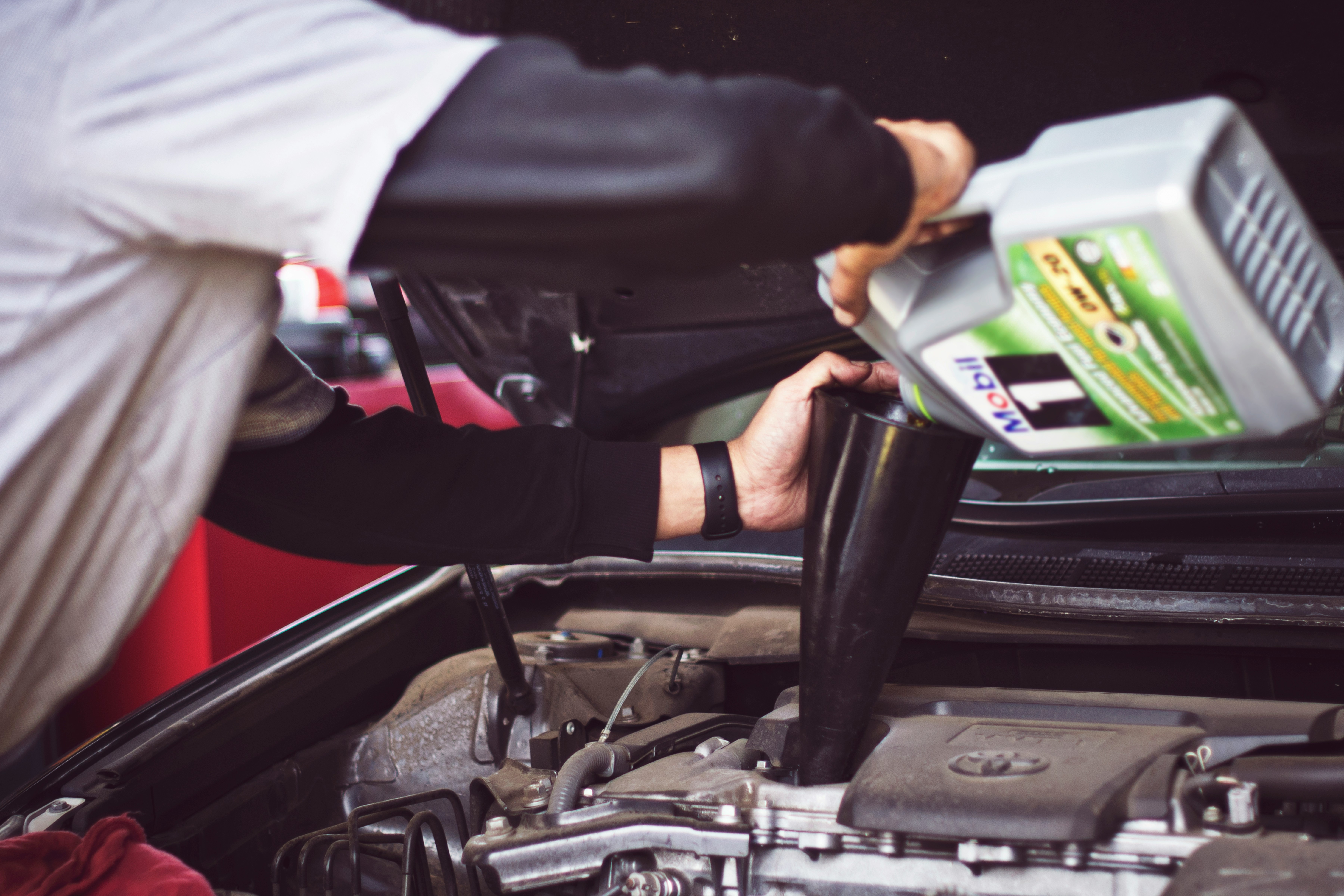 Mechanic pouring factory-spec Mobil 1 oil into an Audi engine bay